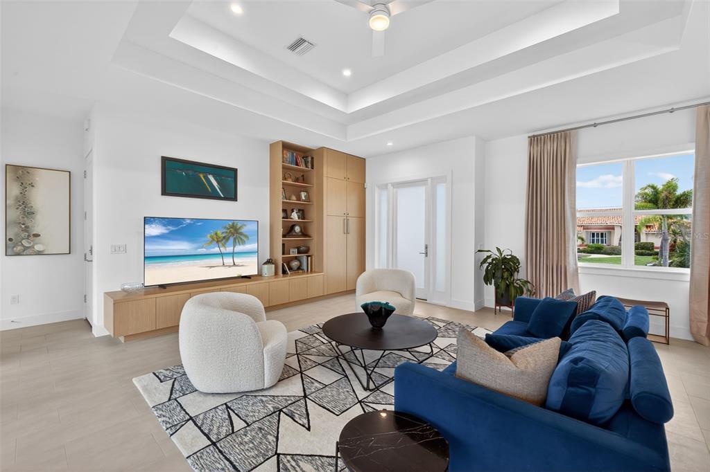 A modern living room features a blue sofa, white armchairs, and built-in wooden shelving — 3363 TRINIDAD COURT, PUNTA GORDA, FL