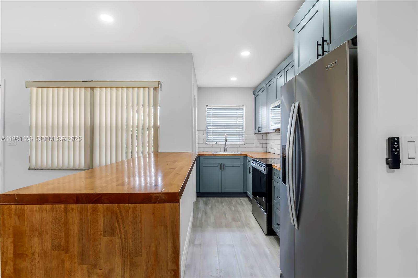 A kitchen features blue cabinets, a wooden countertop breakfast bar, and stainless steel appliances — 5300 Washington St # A137, Hollywood FL 33021, HOLLYWOOD, FL