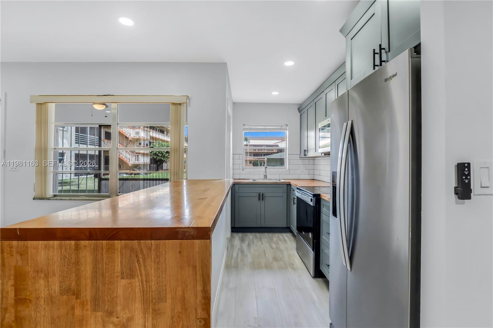 A kitchen features gray cabinets, a wooden countertop breakfast bar, and stainless steel appliances — 5300 Washington St # A137, Hollywood FL 33021, HOLLYWOOD, FL