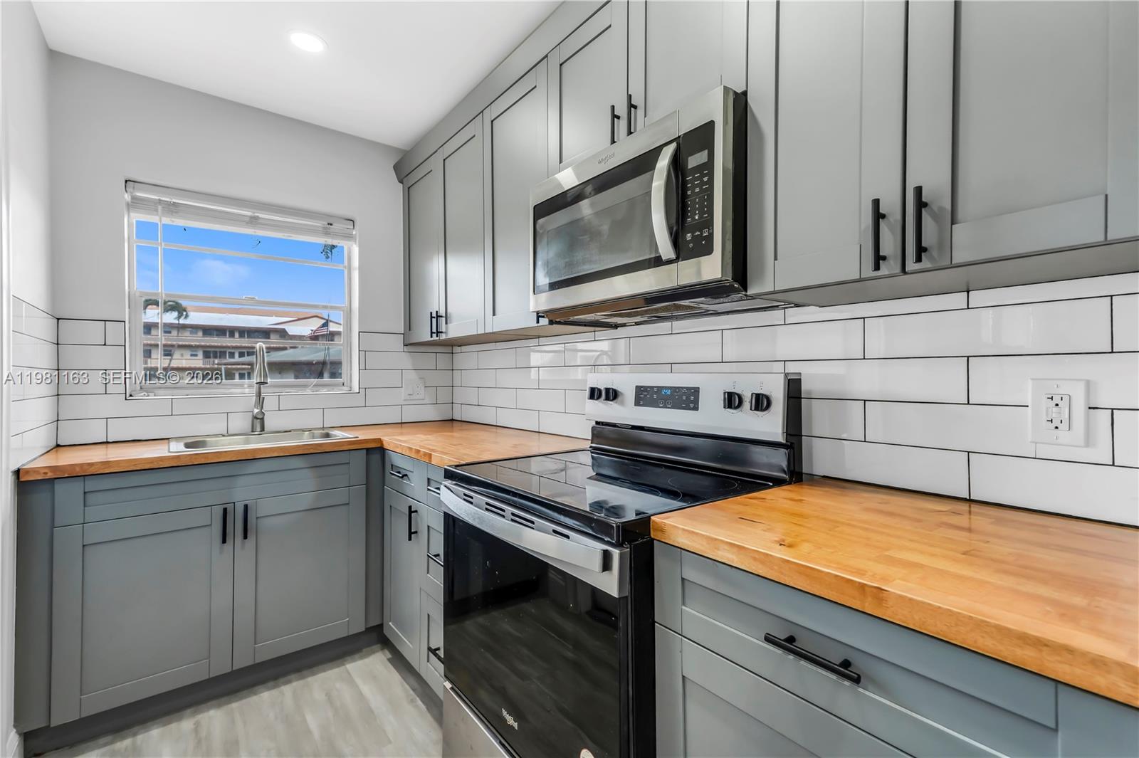 A kitchen features gray cabinets, wood countertops, white subway tile backsplash, and stainless steel appliances — 5300 Washington St # A137, Hollywood FL 33021, HOLLYWOOD, FL