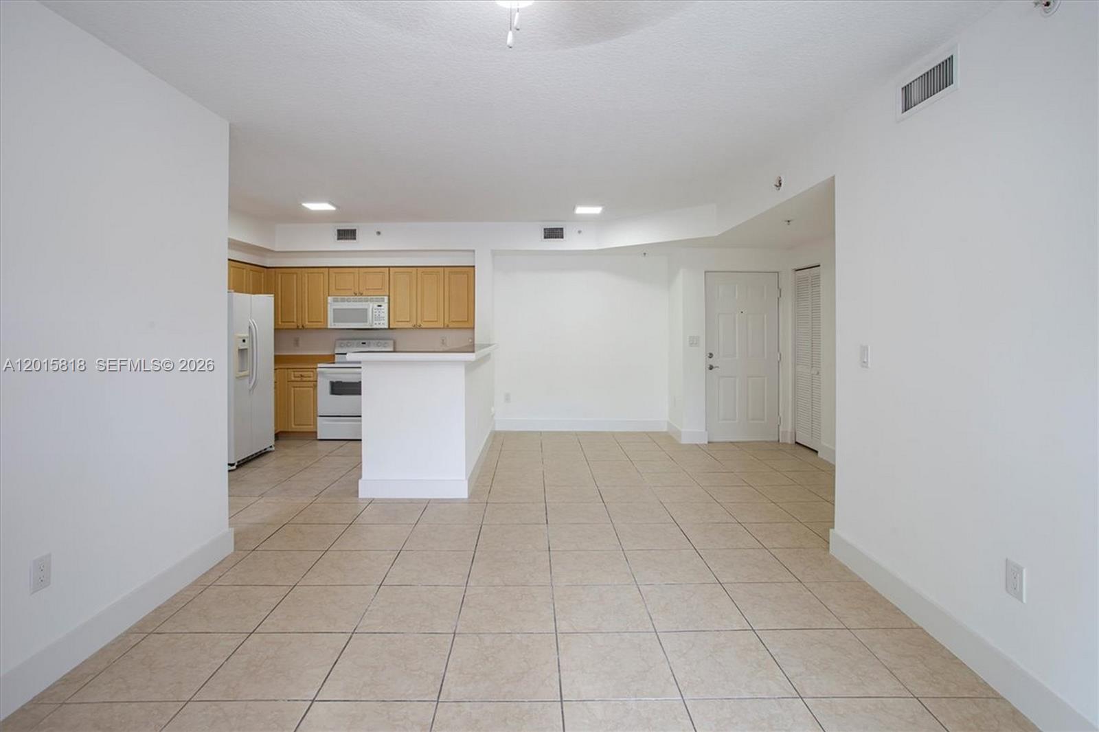 An open-concept kitchen with light wood cabinets and a breakfast bar overlooks a tiled room — 6861 SW 44th St # 109, Miami FL 33155, MIAMI, FL