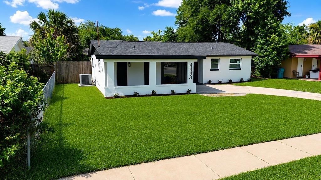 A single-story house with a white exterior, dark roof, and a large front lawn — 4443 KING COLE BOULEVARD, ORLANDO, FL
