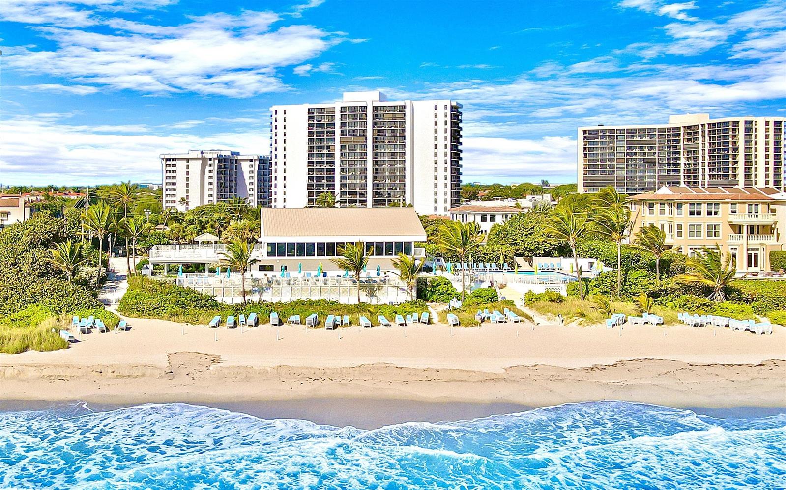 An aerial view of a beachside resort with a pool, palm trees, and tall buildings — 4748 S Ocean Boulevard # a, Highland Beach FL 33487, HIGHLAND BEACH, FL