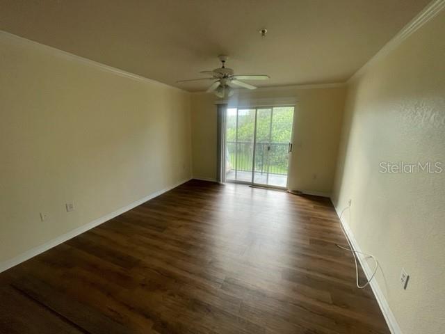 An empty room features wood-look flooring, a ceiling fan, and a sliding glass door to a balcony — 18108 PERREGRINES PERCH PLACE UNIT 211, LUTZ, FL