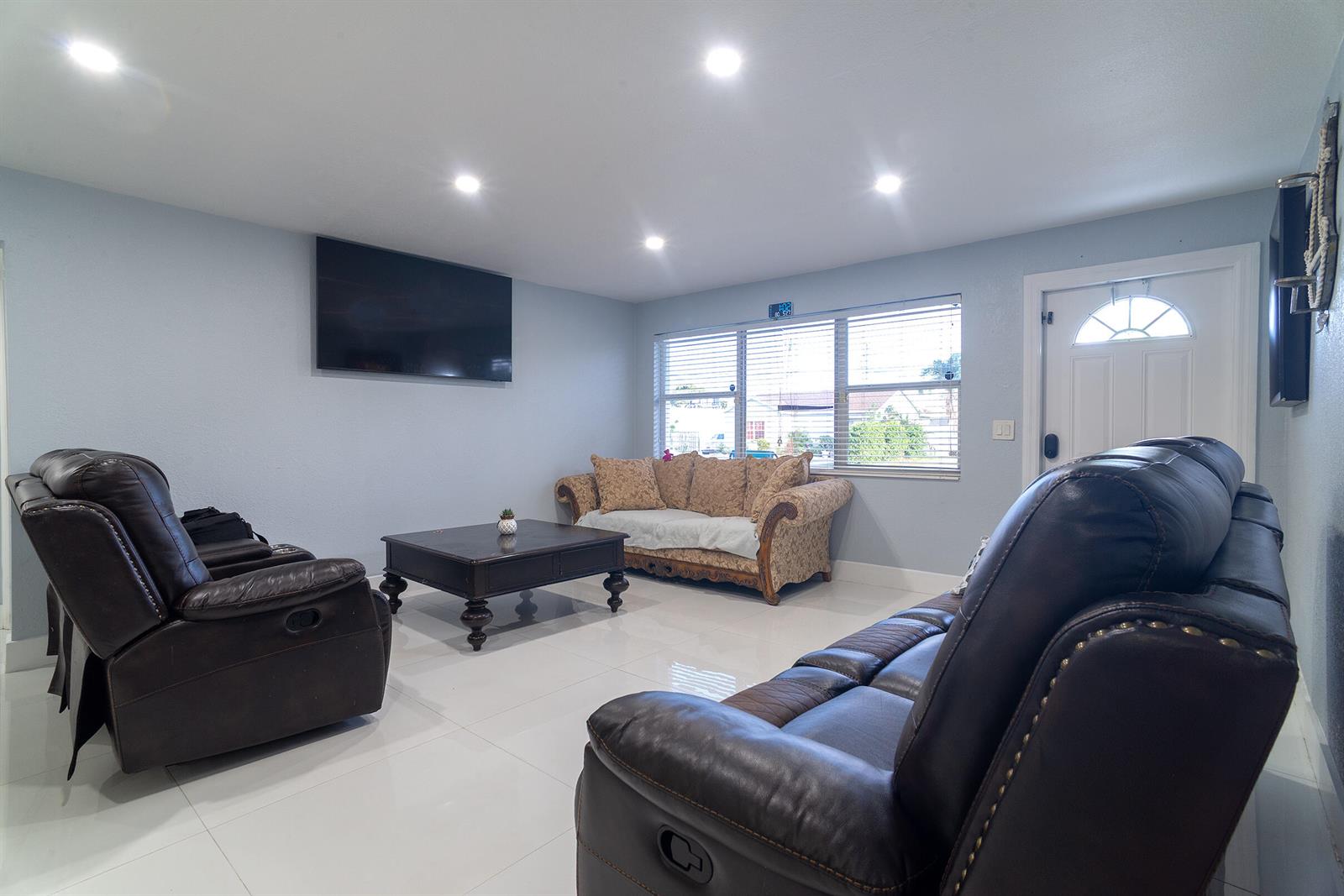 A living room features dark leather recliners, a patterned sofa, and white tile flooring — 506 Worthmore Drive, FL 33460, FL