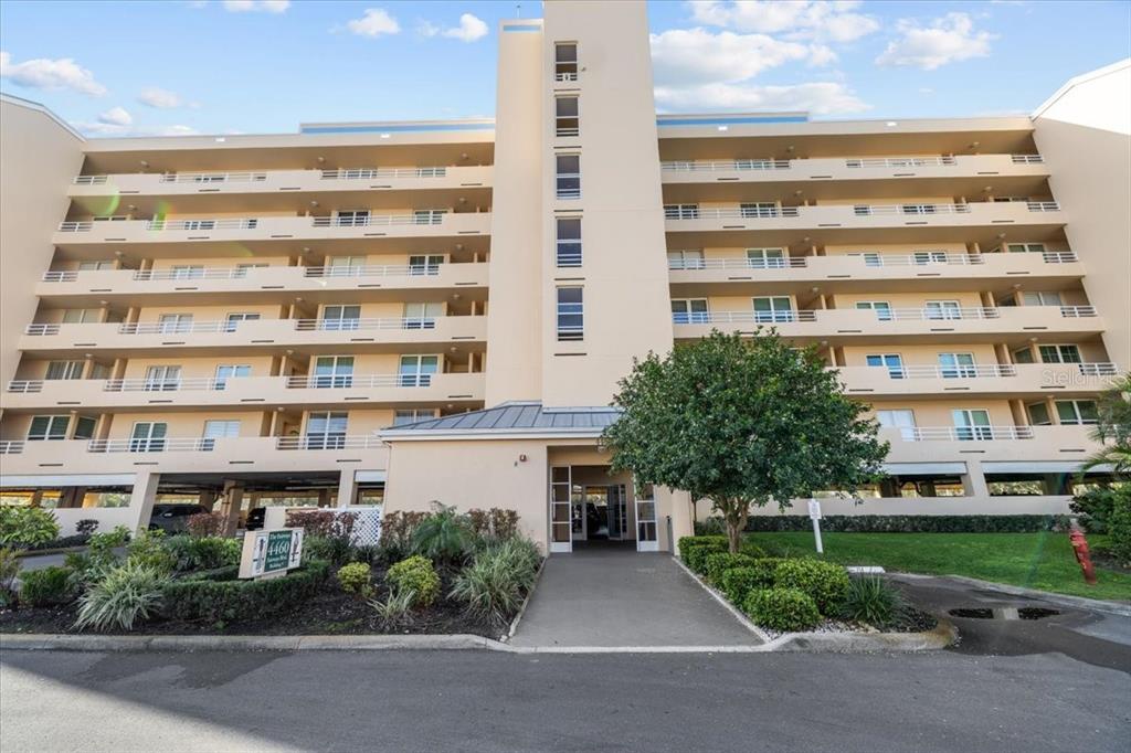 A multi-story apartment building with balconies and a central entrance under a blue sky — 4460 FAIRWAYS BOULEVARD UNIT 407, BRADENTON, FL
