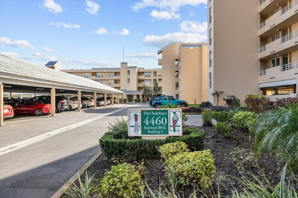 An exterior view of a multi-story apartment building with a covered parking area — 4460 FAIRWAYS BOULEVARD UNIT 407, BRADENTON, FL