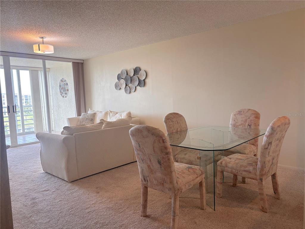 A living and dining area features a white sofa, glass table, and patterned chairs — 4460 FAIRWAYS BOULEVARD UNIT 407, BRADENTON, FL