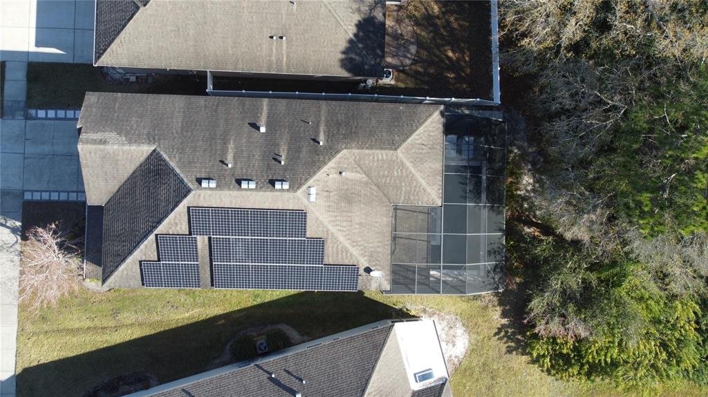 An aerial view shows a house roof with solar panels and a screened-in pool enclosure — 11403 QUIET FOREST DRIVE, TAMPA, FL