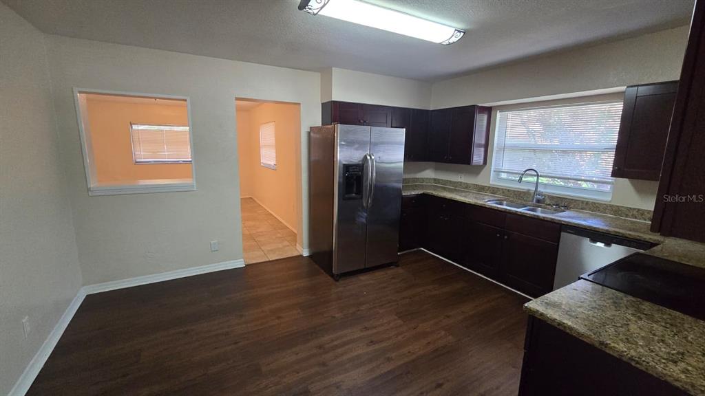 This kitchen features dark wood cabinets, stainless steel appliances, and wood-look flooring — 14857 SUNSET STREET, CLEARWATER, FL
