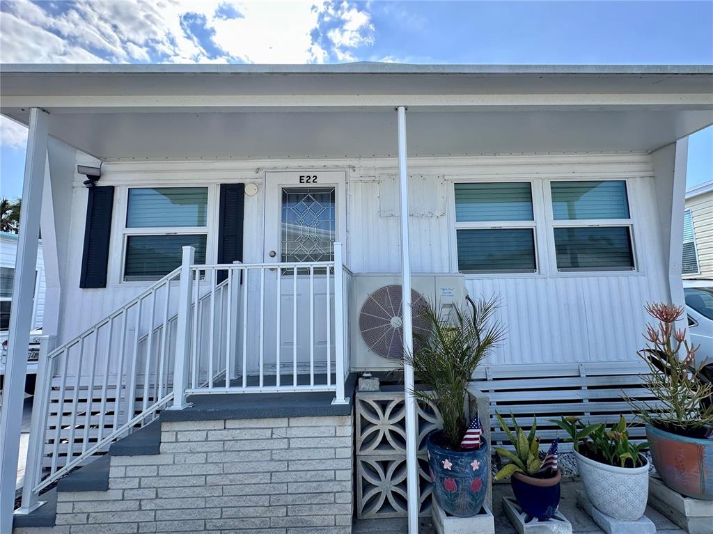 The exterior of a white mobile home features a brick staircase, a railing, and potted plants — 3710 GULF OF MEXICO DRIVE UNIT E22, LONGBOAT KEY, FL