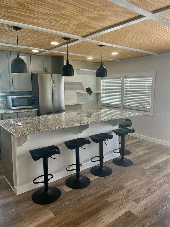 A kitchen features a granite-topped island, four black bar stools, and a wood-paneled ceiling — 3710 GULF OF MEXICO DRIVE UNIT E22, LONGBOAT KEY, FL
