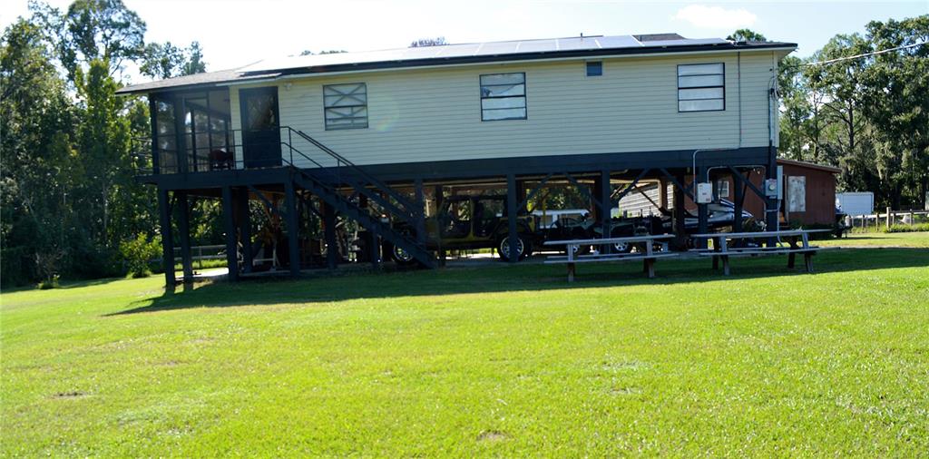 An aerial view of a stilt house with solar panels on the roof and surrounding land — 4424 ROSE STREET, VALRICO, FL