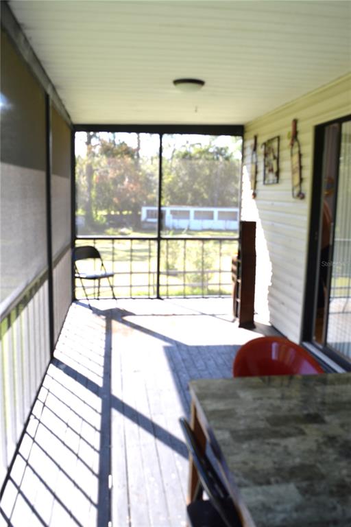 A screened-in porch features a wooden deck, a metal chair, and a stone-topped table — 4424 ROSE STREET, VALRICO, FL