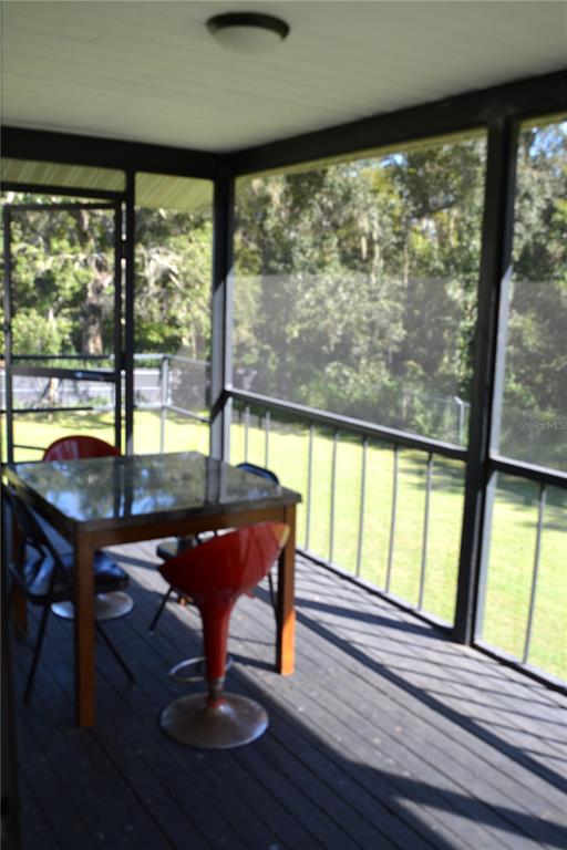 A screened-in porch features a dark wooden deck, a square table, and red bar stools — 4424 ROSE STREET, VALRICO, FL