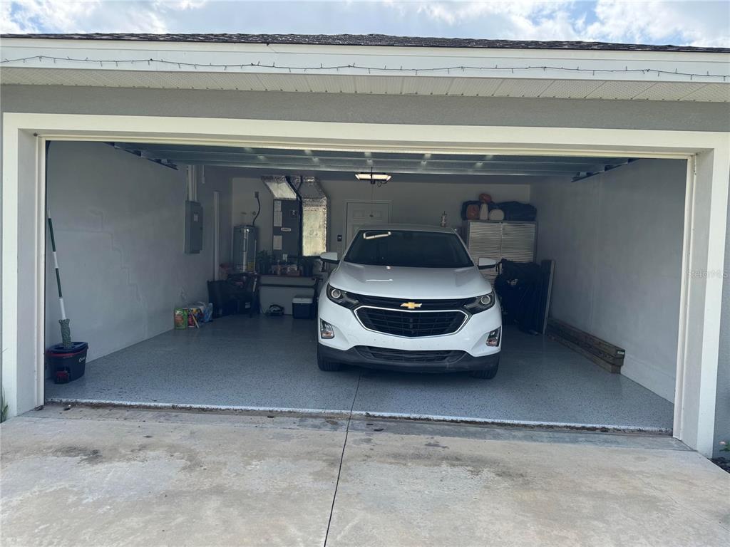 A two-car garage with a white SUV, epoxy flooring, and a water heater — 19 WILLOW RUN, OCALA, FL