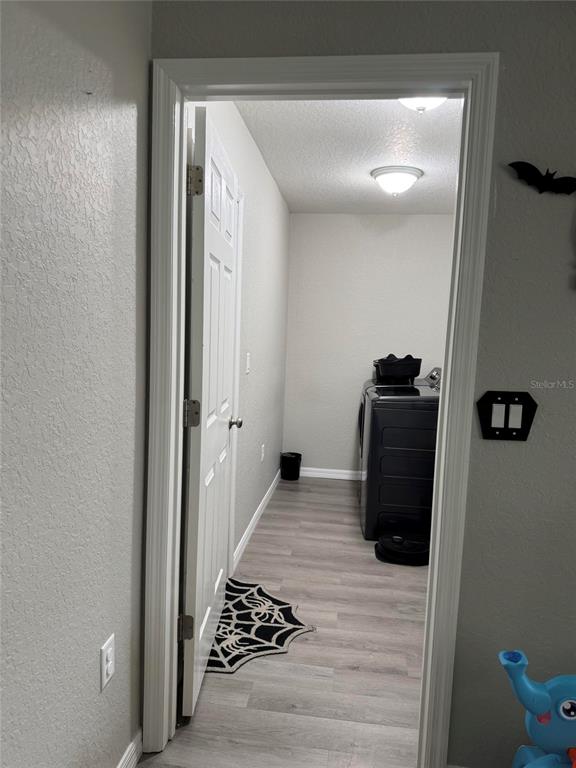 A doorway opens into a laundry room featuring light wood-look flooring and a black appliance — 19 WILLOW RUN, OCALA, FL