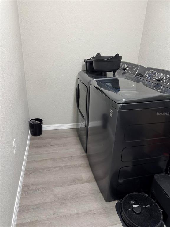A laundry room features grey appliances, light wood-look flooring, and neutral walls — 19 WILLOW RUN, OCALA, FL
