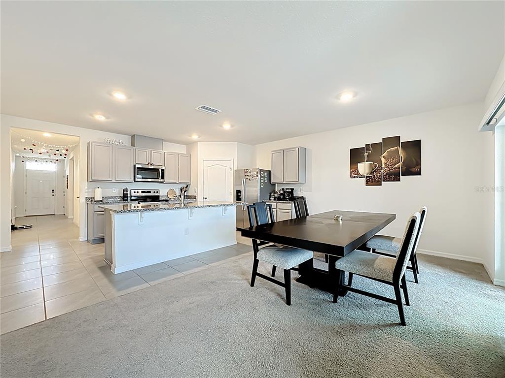 A kitchen with light gray cabinets and a granite island opens to a dining area — 1519 WAX MYRTLE WAY, HAINES CITY, FL