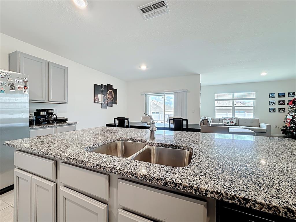 A kitchen island with a granite countertop and double sink overlooks an open-concept living area — 1519 WAX MYRTLE WAY, HAINES CITY, FL