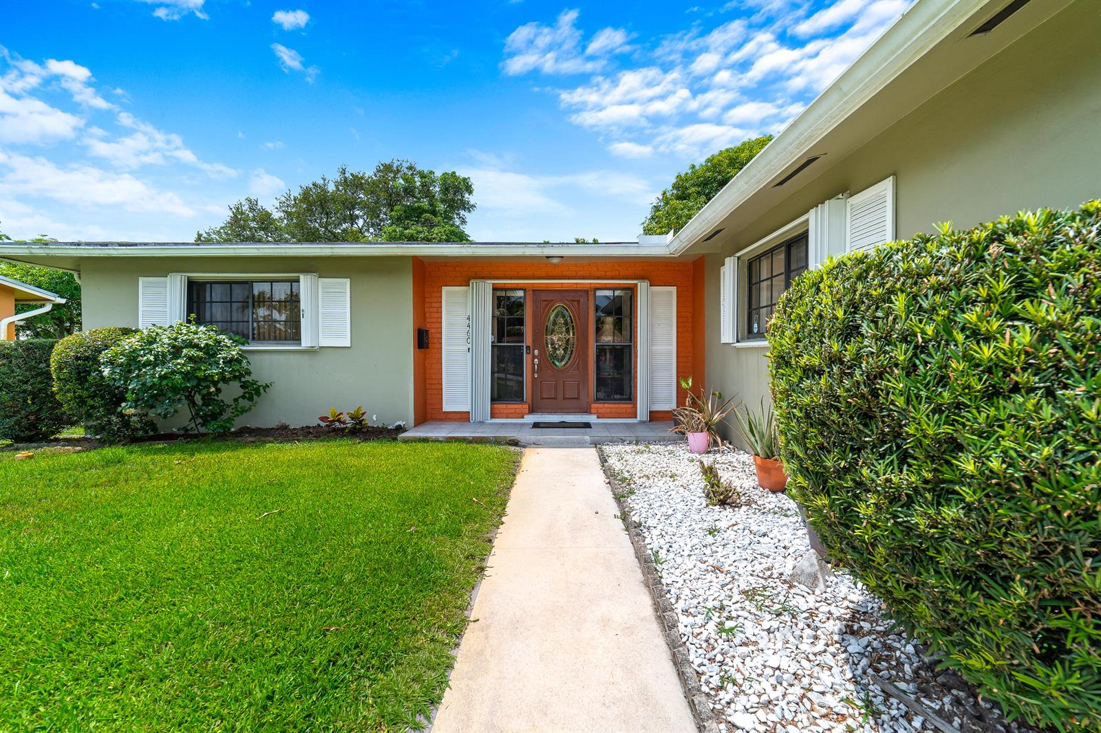 A single-story house with a green exterior, orange brick entryway, and a white stone garden — 4460 NW 3rd Place, Plantation FL 33317, PLANTATION, FL