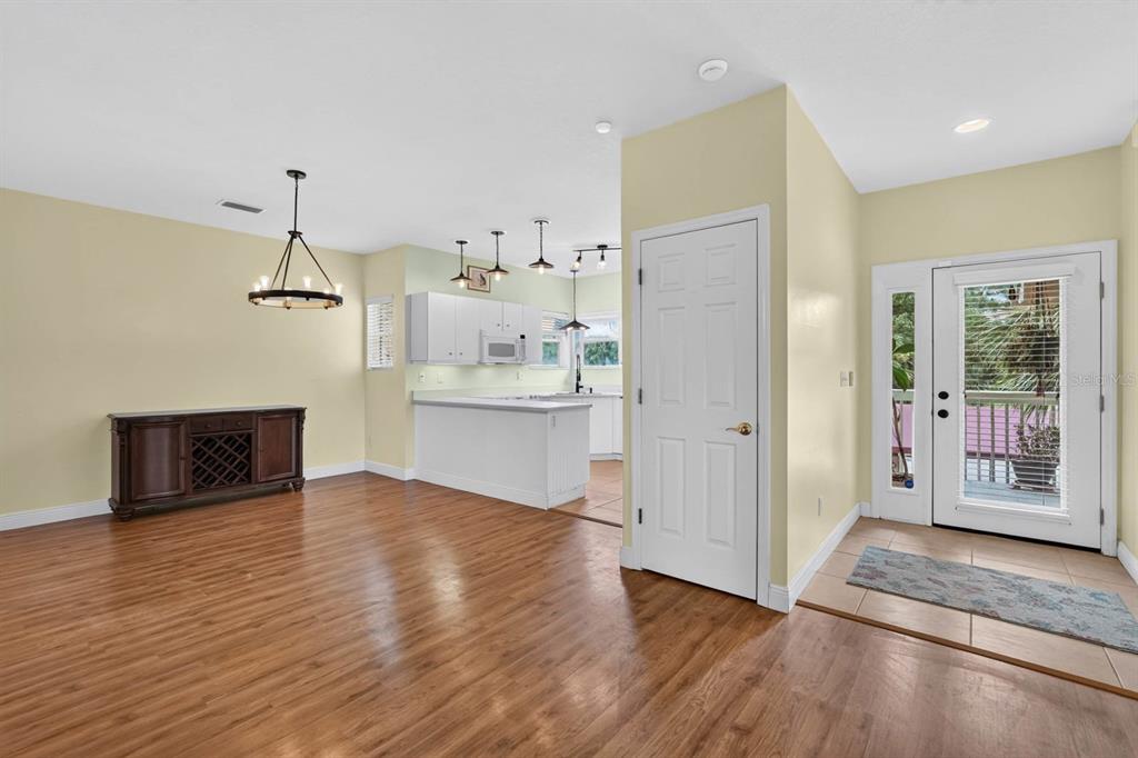 A dining area with wood flooring leads to a kitchen with white cabinets and an entryway — 31 MAGNOLIA DRIVE S, ORMOND BEACH, FL