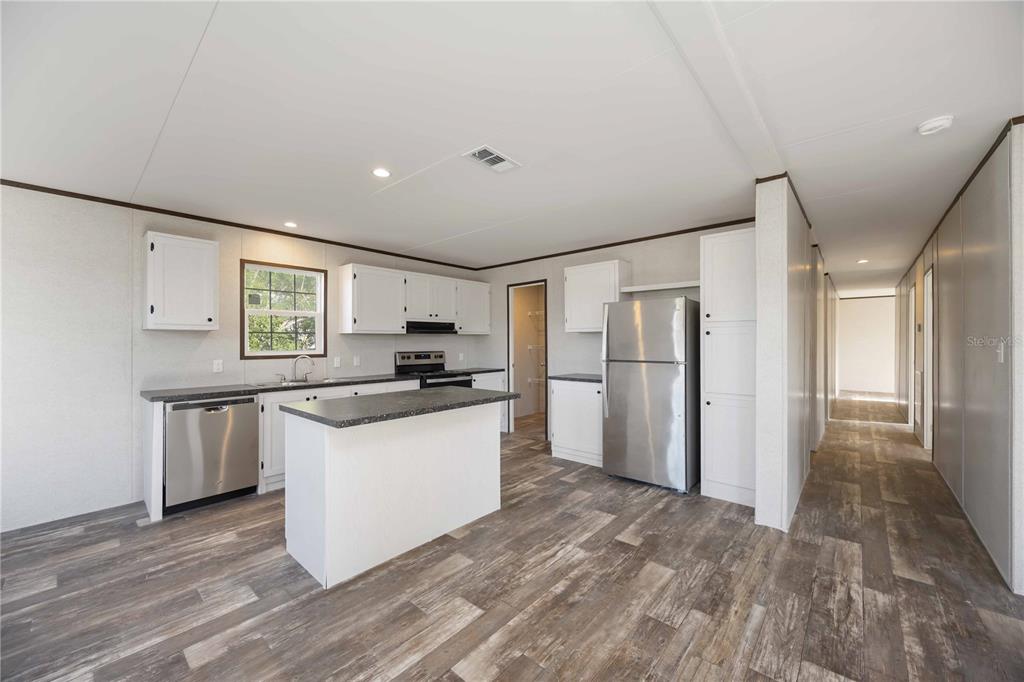A kitchen with white cabinets, stainless steel appliances, a center island, and wood-look flooring — 4780 DUNCAN ROAD, PUNTA GORDA, FL