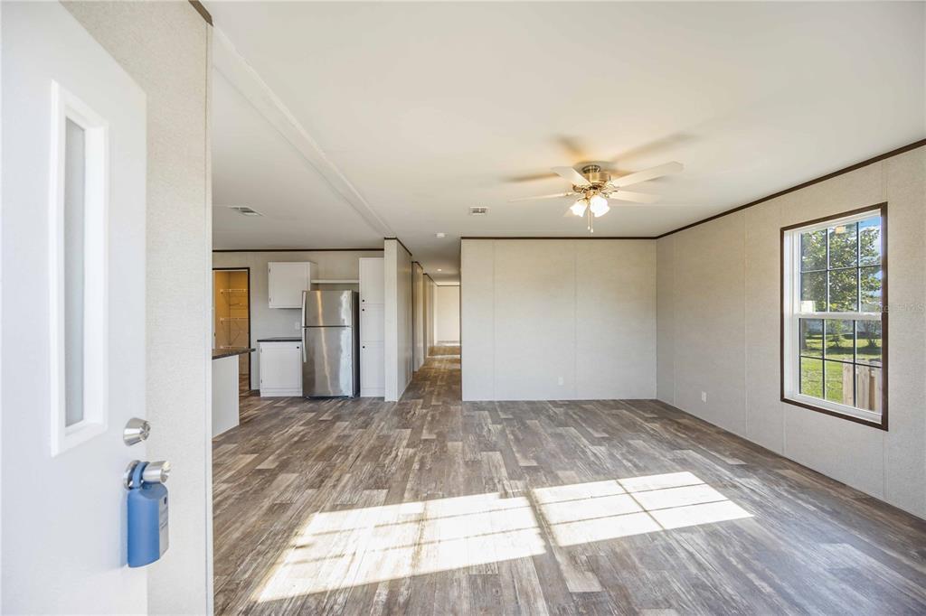 An open-concept living area with wood-look flooring leads into a kitchen with stainless steel appliances — 4780 DUNCAN ROAD, PUNTA GORDA, FL
