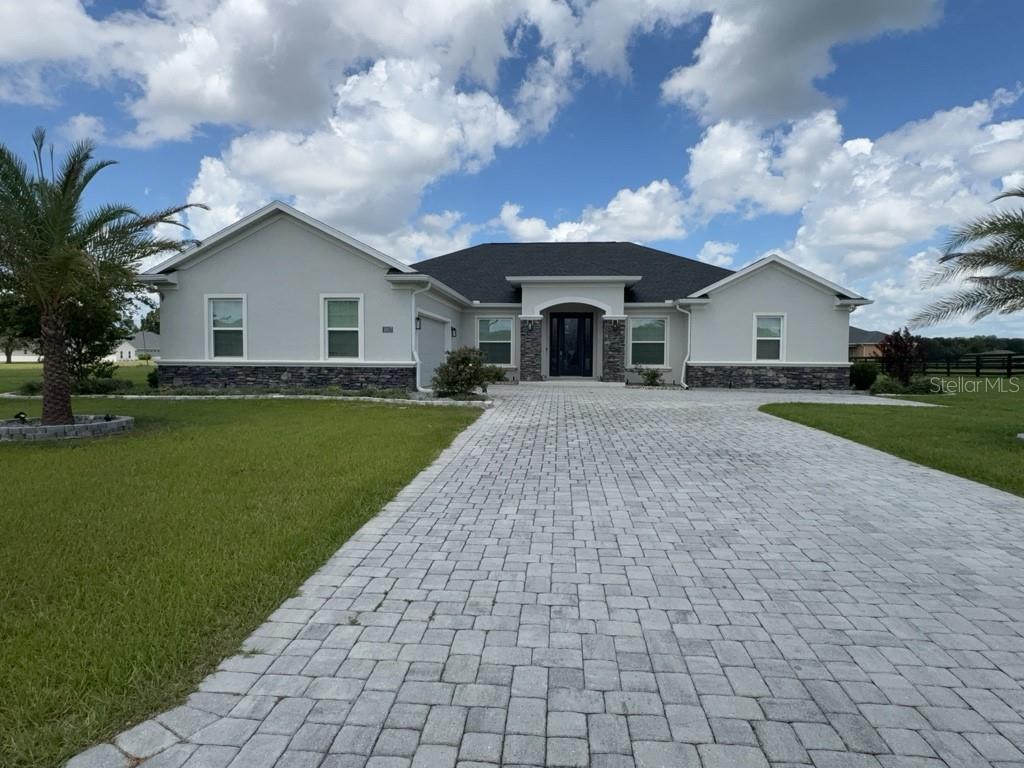 A single-story house with a stone veneer base, light gray stucco, and a paved driveway — 1817 NW 83RD LOOP, OCALA, FL