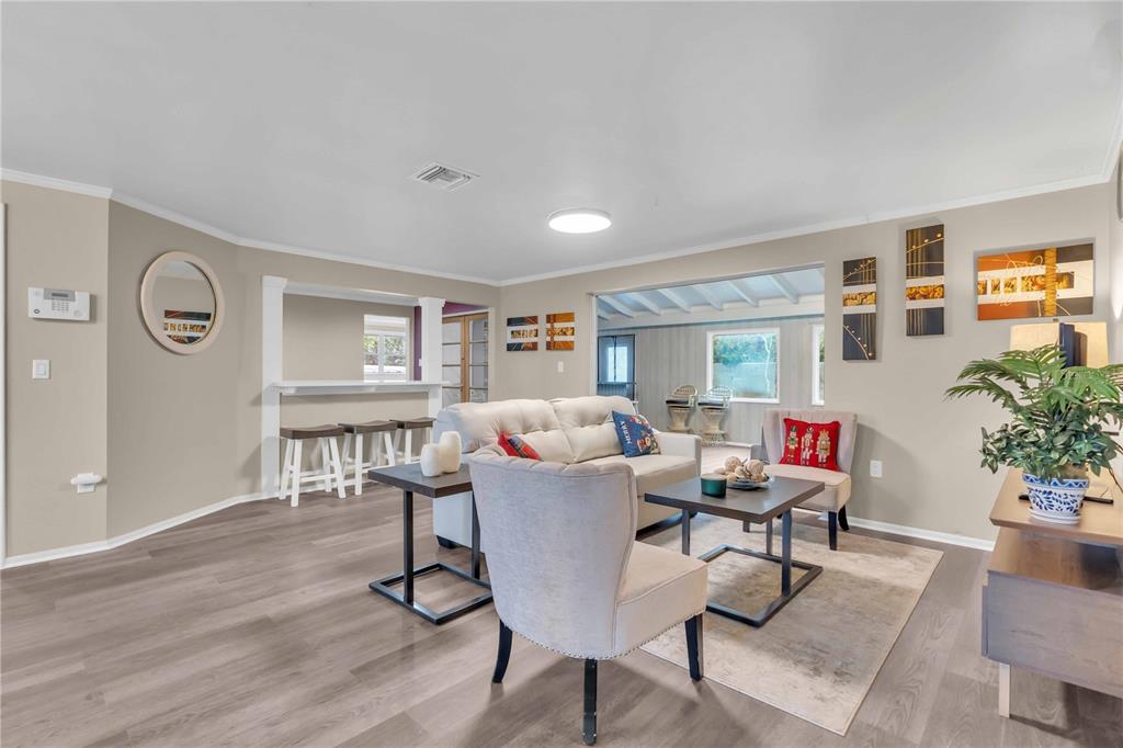 A living room features light gray wood-look flooring, a beige sofa, and a breakfast bar — 7420 CASS CIRCLE, SARASOTA, FL