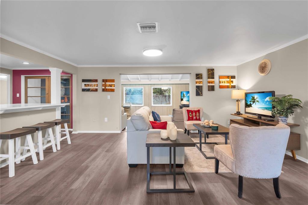 A living room with wood-look flooring, a white sofa, and a television on a console — 7420 CASS CIRCLE, SARASOTA, FL