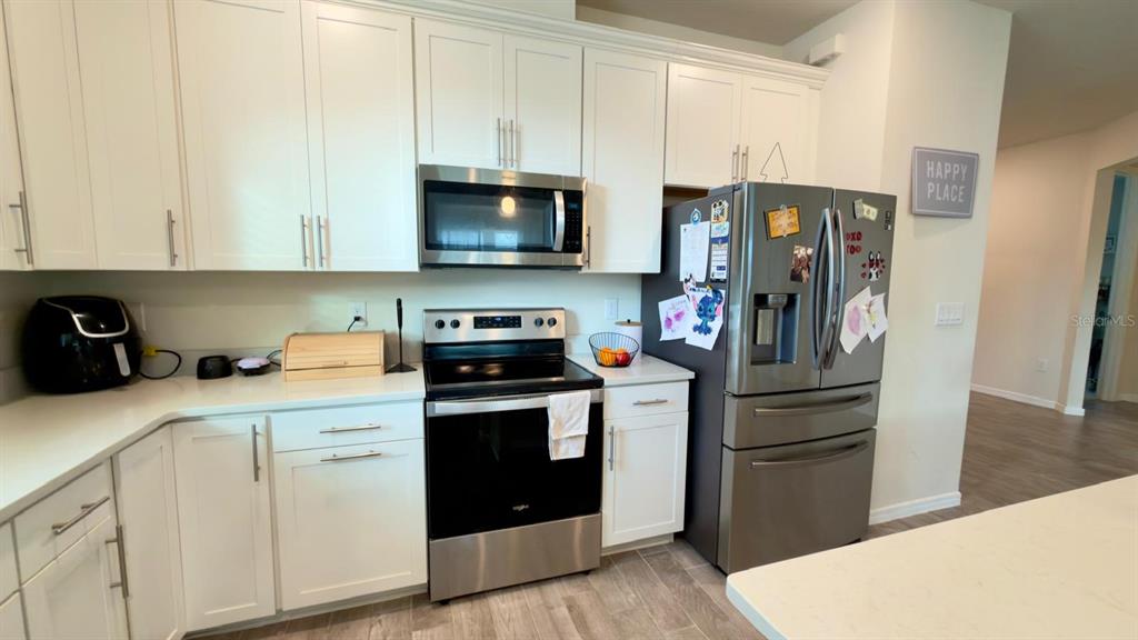 A living room with a gray sectional sofa opens into a kitchen with white cabinets — 4620 GLIDING WAVE ST, WINTER GARDEN, FL