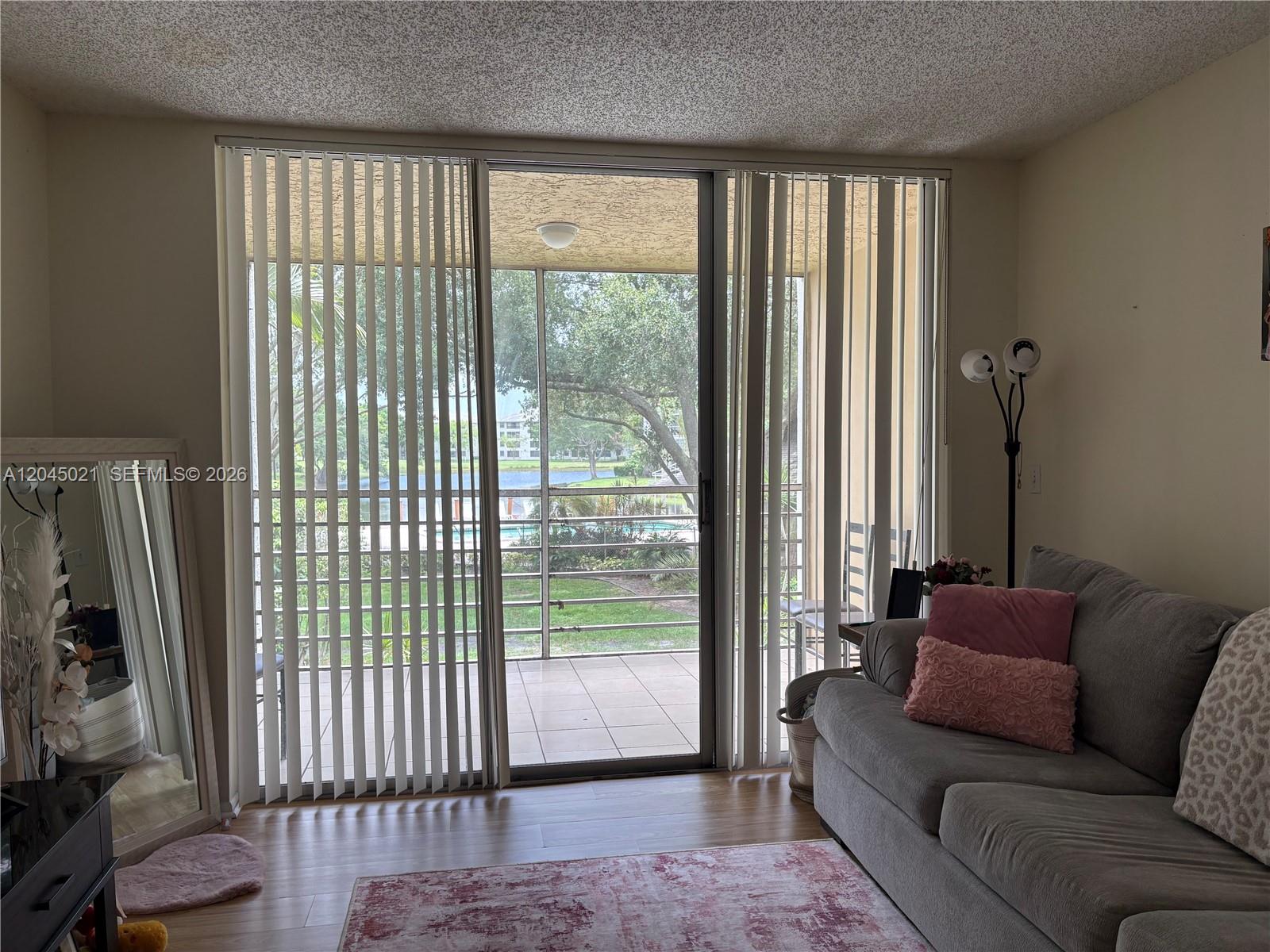 A living room features a sliding glass door leading to a screened balcony with water views — 9340 Lagoon Pl # 202, Davie FL 33324, DAVIE, FL
