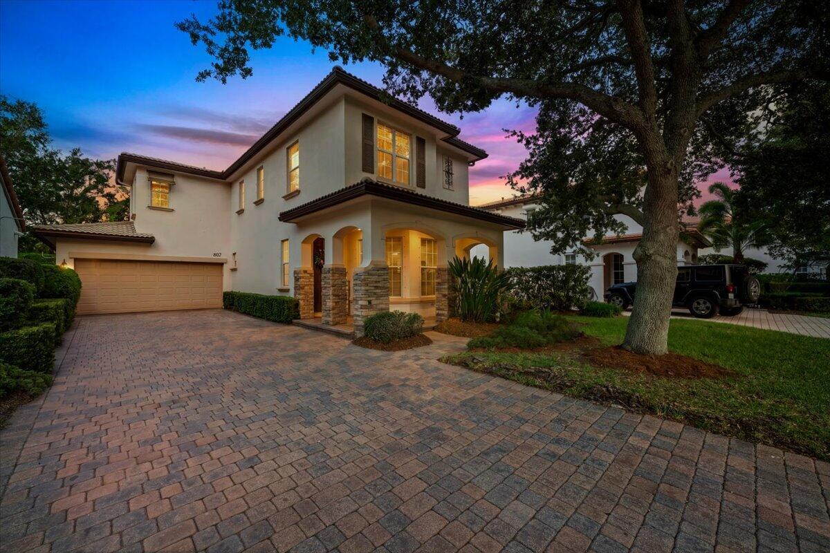 A two-story house with a paved driveway, stone accents, and a large tree in front — 603 Castle Drive, Palm Beach Gardens FL 33410, PALM BEACH GARDENS, FL