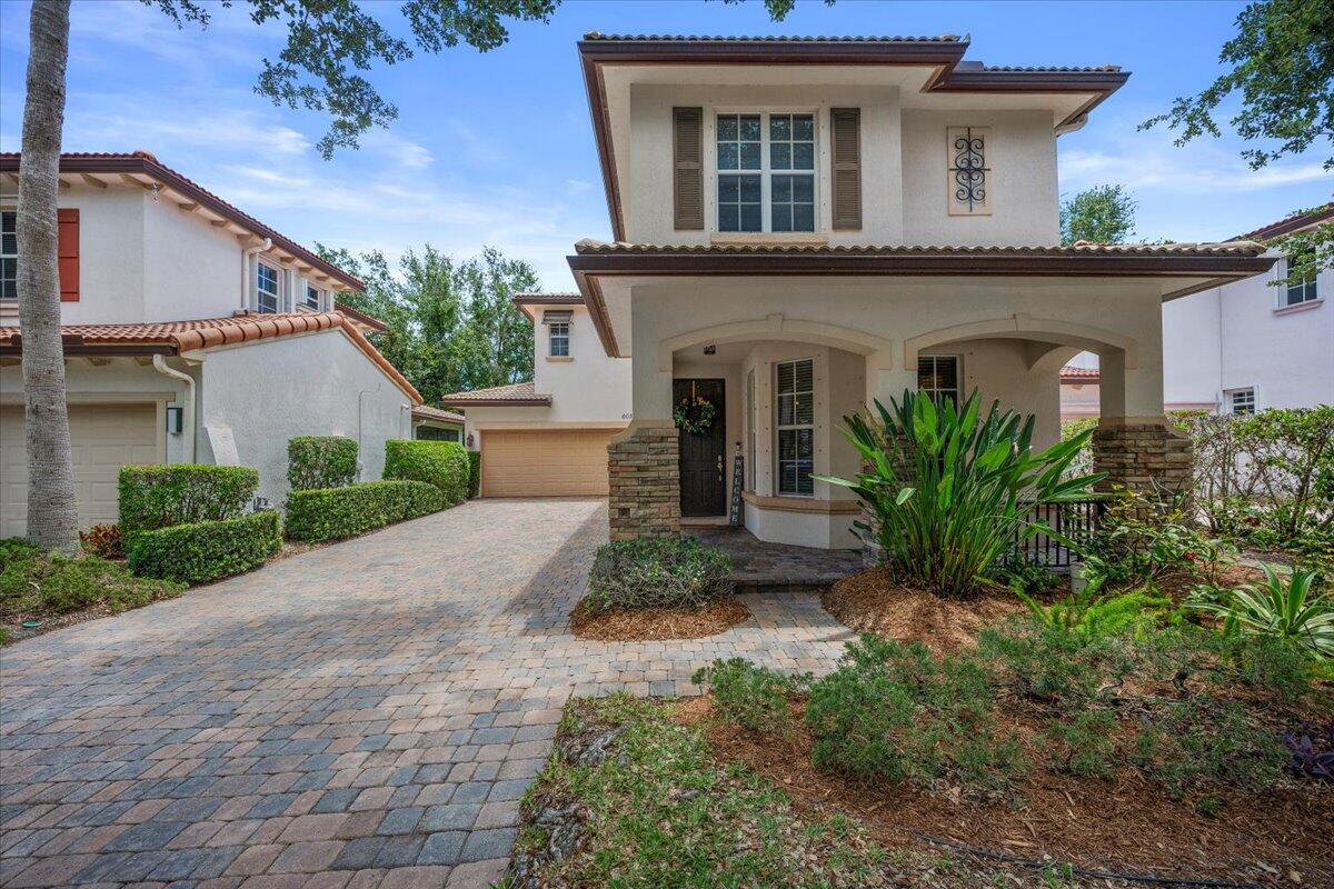 A two-story house with a stone-accented porch, a paved driveway, and a tiled roof — 603 Castle Drive, Palm Beach Gardens FL 33410, PALM BEACH GARDENS, FL