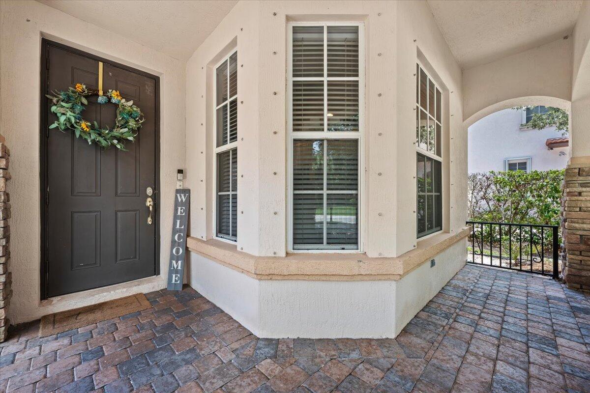 A covered entryway features a dark door with a wreath, a welcome sign, and windows — 603 Castle Drive, Palm Beach Gardens FL 33410, PALM BEACH GARDENS, FL