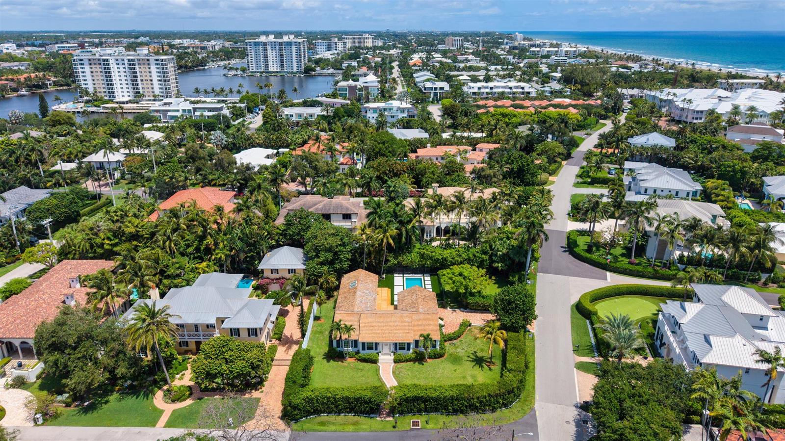 An aerial view shows a residential neighborhood with houses, lush trees, and a nearby coastline — 1017 Tamarind Road, Delray Beach FL 33483, DELRAY BEACH, FL