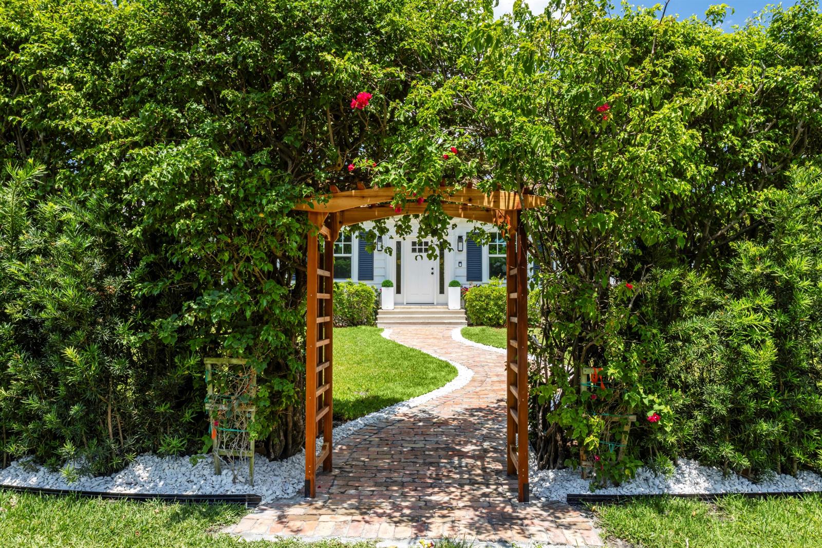 A wooden arbor stands over a brick walkway leading to a house with blue shutters — 1017 Tamarind Road, Delray Beach FL 33483, DELRAY BEACH, FL