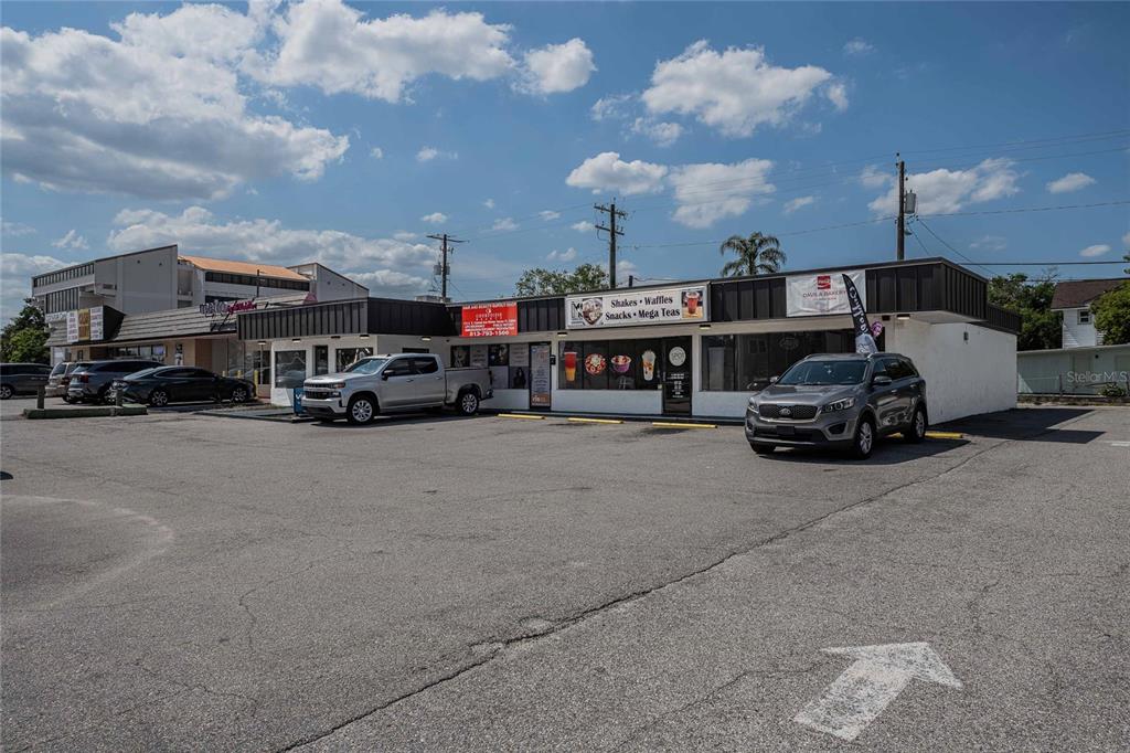 A commercial strip mall building with a parking lot in front under a blue sky — 211 E CENTRAL AVENUE, WINTER HAVEN, FL