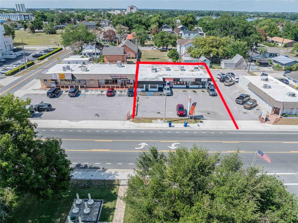 An aerial view shows a commercial strip mall building outlined in red with a parking lot — 211 E CENTRAL AVENUE, WINTER HAVEN, FL