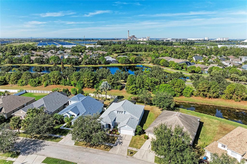 An aerial view shows suburban houses with gray roofs situated near a lake and trees — 7114 CROMWELL PARK LANE, APOLLO BEACH, FL