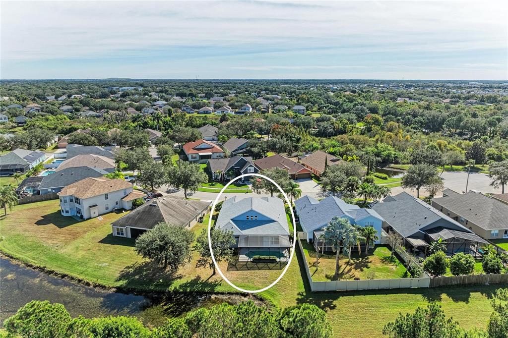 An aerial view shows a single-family house with a screened pool and backyard pond — 7114 CROMWELL PARK LANE, APOLLO BEACH, FL