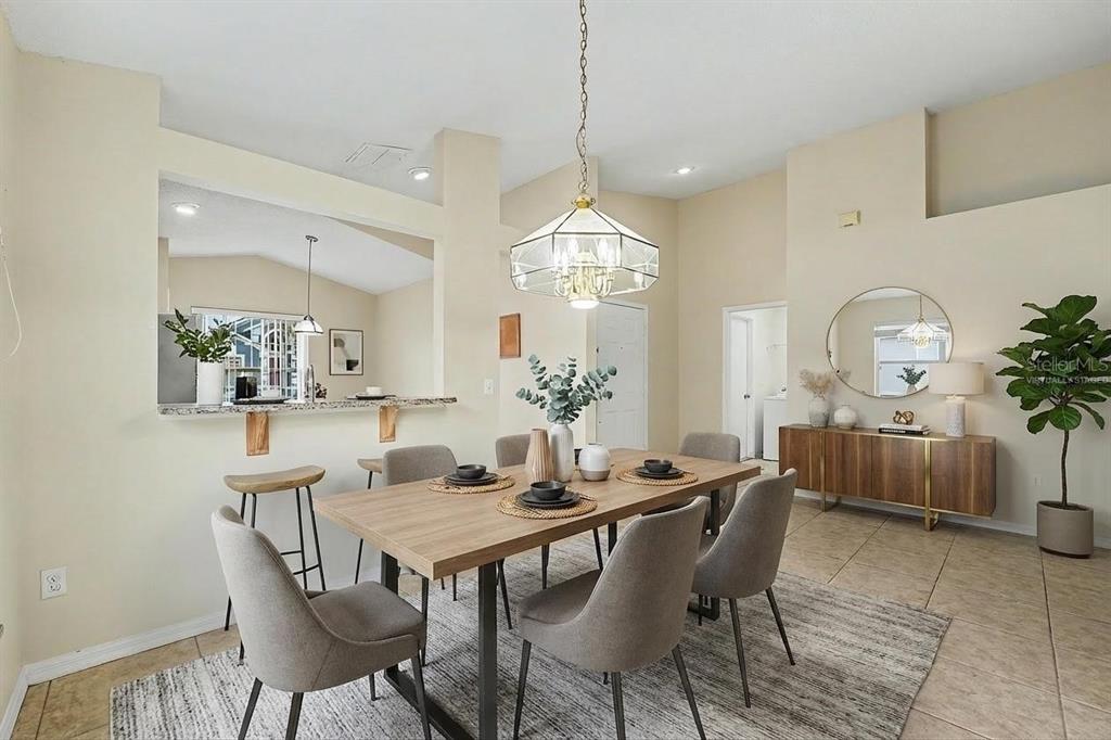 A dining room with a wooden table, grey chairs, a pendant light, and a breakfast bar — 162 CANARY ISLAND CIRCLE, DAVENPORT, FL