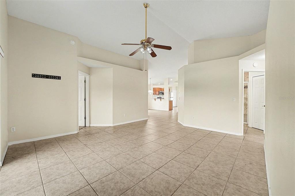 An open-concept living area features beige tile flooring, vaulted ceilings, and a brass ceiling fan — 162 CANARY ISLAND CIRCLE, DAVENPORT, FL