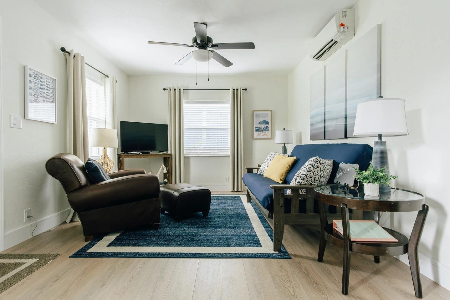 A living room features a blue futon, a brown leather armchair, and a blue rug — 213 Hibiscus Avenue, Pompano Beach FL 33062, POMPANO BEACH, FL