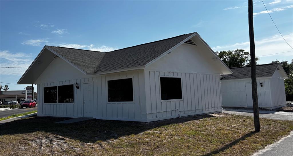 A white, single-story commercial building with board-and-batten siding and a dark shingled roof — 5417 GRAND BOULEVARD UNIT B, NEW PORT RICHEY, FL