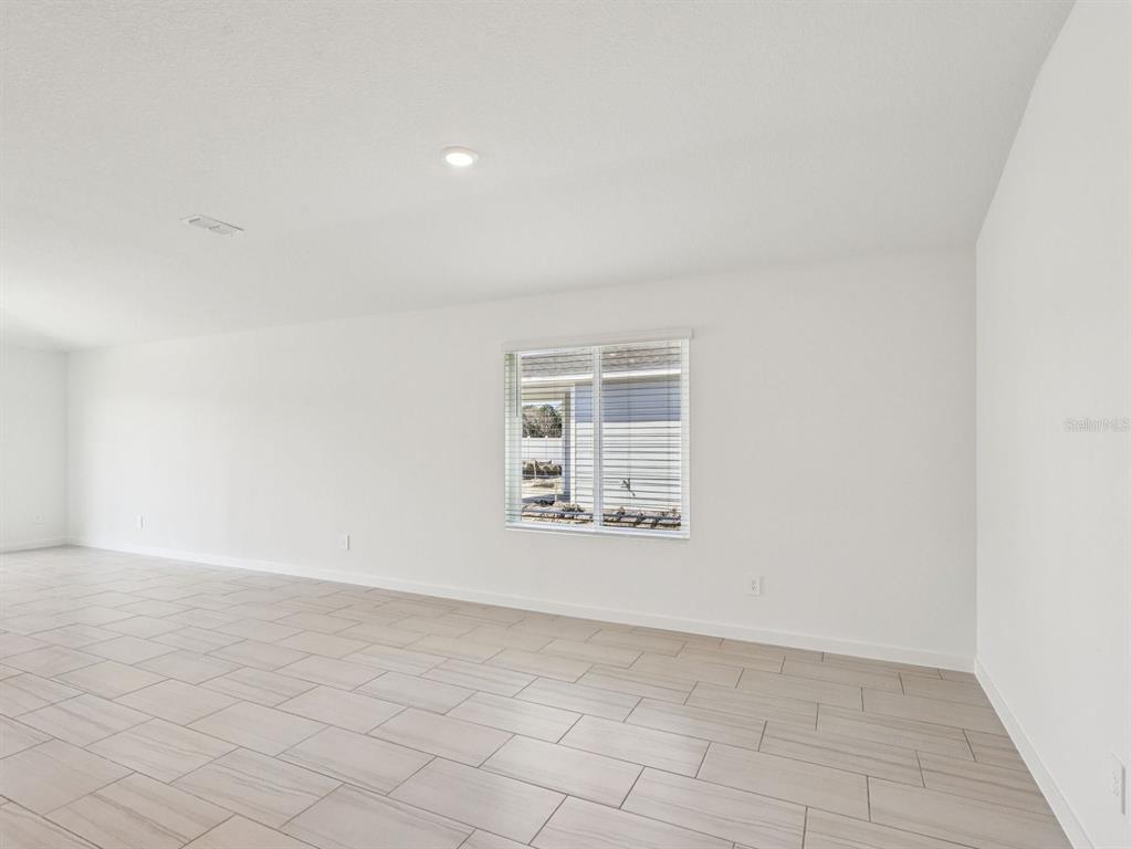 A bright, empty room features white walls, light-colored tile flooring, and a single window — 78 ARARAT DRIVE, PALM COAST, FL