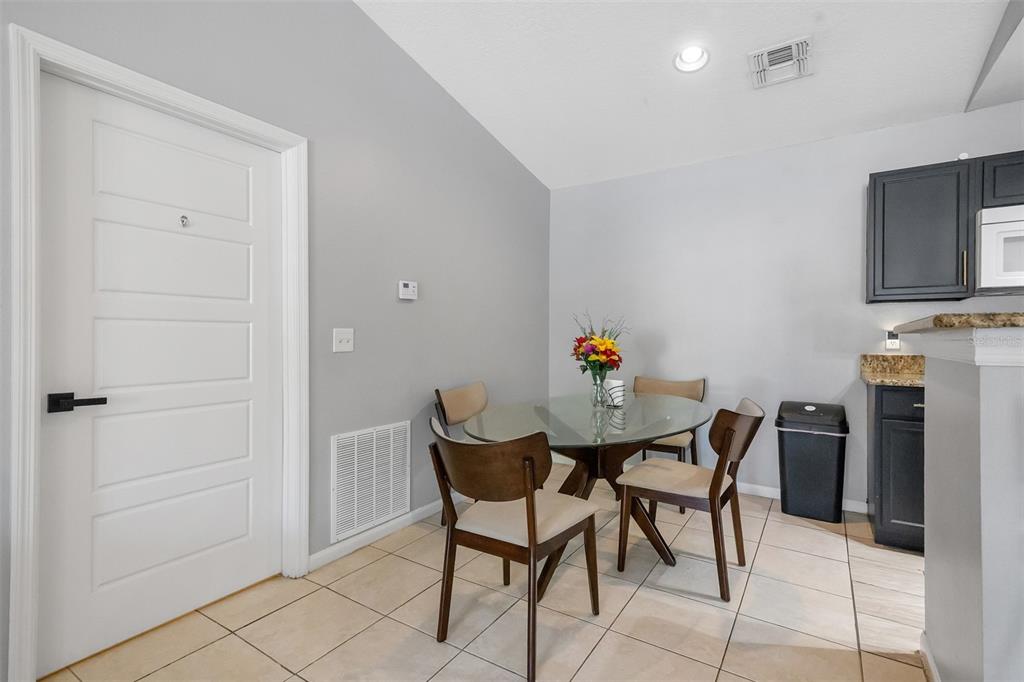A dining area features a glass table, four chairs, tile flooring, and dark kitchen cabinets — 4360 S KIRKMAN ROAD UNIT 408, ORLANDO, FL