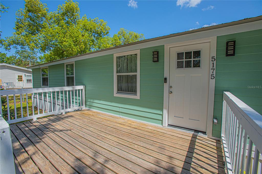 A wooden deck leads to the front door of a light green house — 5175 COUNTRYSIDE COURT, ST CLOUD, FL