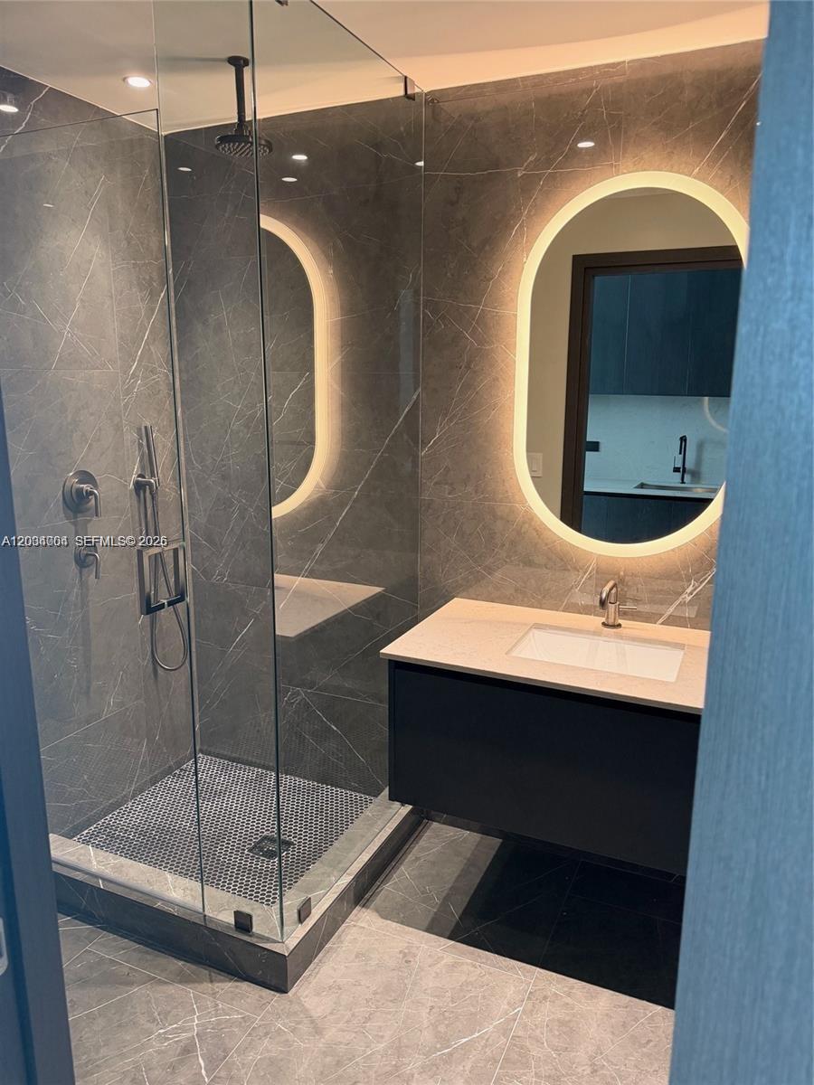 A modern bathroom features a glass-enclosed shower, a floating vanity, and an illuminated oval mirror — 20 NE 11th St # 3703A, Miami FL 33132, MIAMI, FL